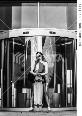 Woman on a skateboard in the city. Beautiful contrasting black and white photo of a woman riding around the city. Woman on a skateboard in the city. Beautiful contrasting black and white photo of a woman riding around the city. 92791435