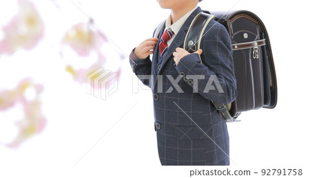 A boy carrying a black school bag and staring at flowers A boy carrying a black school bag and staring at flowers 92791758
