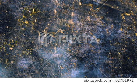 Aerial drone view flight over black ash of field of burned brown yellow dry grass and white smoke on sunny autumn day. View from above. Texture natural background of ecological environmental disaster. Aerial drone view flight over black ash of field of burned brown yellow dry grass and white smoke on sunny autumn day. View from above. Texture natural background of ecological environmental disaster. 92791972
