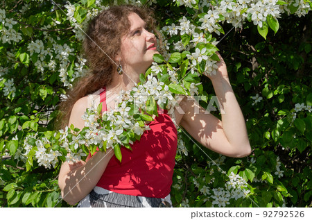 Portrait of beautiful young woman in apple trees blooming park on a sunny day. Springtime 92792526