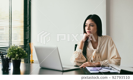Pensive young businesswoman looking through glass office window, dreaming about good future 92793510