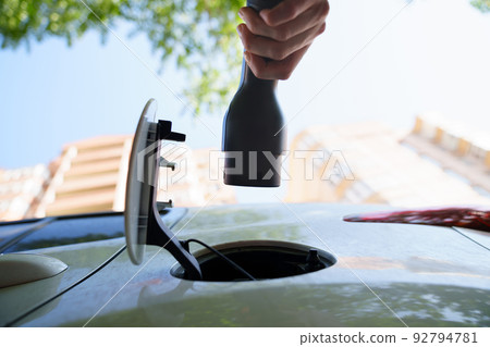 hand of woman plugging in an electric car at outlet socket. 92794781