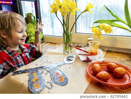 boy drawing the ears of a handmade Easter bunny made of cardboard. Preparation for the celebration of the Easter holiday. boy drawing the ears of a handmade Easter bunny made of cardboard. Preparation for the celebration of the Easter holiday. 92795661