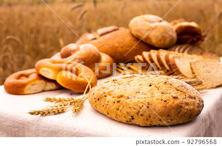 lot of different flavored bread, wheat, rye, on the table in the field outside 92796568