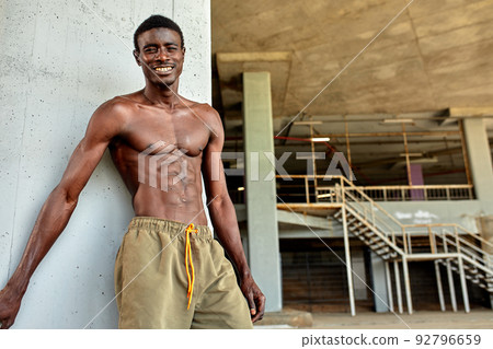 Handsome afro American sportman standing on the street while taking break after training. Black male having rest after workout Handsome afro American sportman standing on the street while taking break after training. Black male having rest after workout 92796659