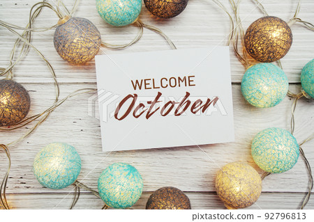 Welcome October text on paper card with LED cotton balls top view on wooden background 92796813