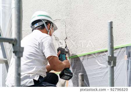 Construction site, exterior wall repair work, multi-tool Construction site, exterior wall repair work, multi-tool 92796820