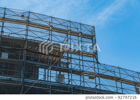 Blue sky and scaffolding and mesh sheets at a construction site Blue sky and scaffolding and mesh sheets at a construction site 92797216