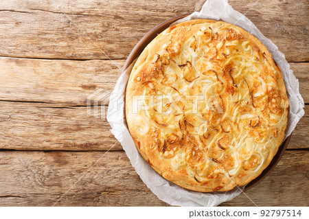 Fugazzeta is a scrumptious cheese stuffed pizza topped with caramelized onions from Argentina closeup in the plate. Horizontal top view Fugazzeta is a scrumptious cheese stuffed pizza topped with caramelized onions from Argentina closeup in the plate. Horizontal top view 92797514