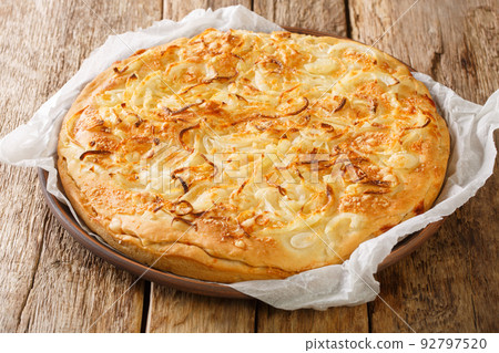 Fugazzeta pizza with onions and mozzarella on a thick crust closeup in the plate. Horizontal Fugazzeta pizza with onions and mozzarella on a thick crust closeup in the plate. Horizontal 92797520