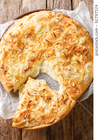 Argentinian Pizza Fugazzeta stuffed with cheese, and topped with the same sweet onions closeup on the wooden table. Vertical top view 92797524
