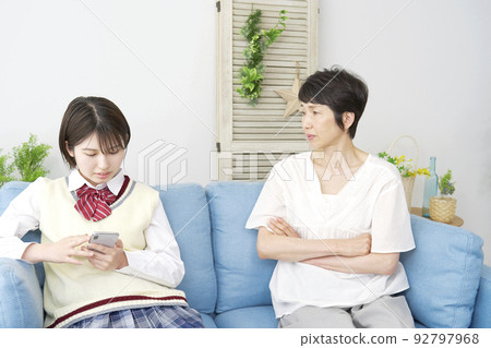 A high school girl using a smartphone scolded by her mother at home 92797968