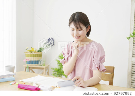 A woman studying at home using a smartphone A woman studying at home using a smartphone 92797992