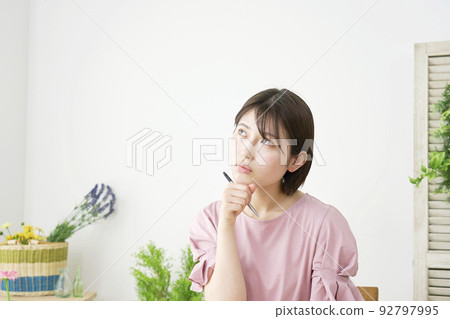 A woman thinking while studying at home A woman thinking while studying at home 92797995