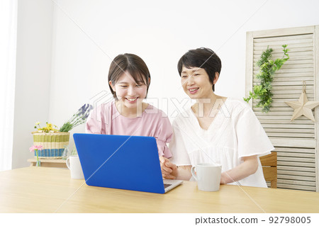 Daughter using laptop with mother at home 92798005
