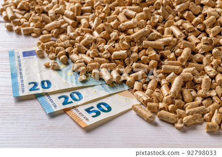 Wood pellets heap and euro money banknotes close-up. Wood pellets heap and euro money banknotes close-up. 92798033