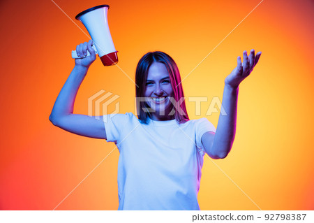 Portrait of young emotional girl, student in white t-shirt isolated on orange color background in neon light. Concept of beauty, fashion, emotions 92798387