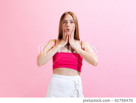 Portrait of young charming girl, student posing isolated on pink background. Concept of beauty, art, fashion, human emotions and facial expressions 92798470