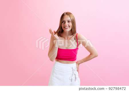 Portrait of young charming girl, student posing isolated on pink background. Concept of beauty, art, fashion, human emotions and facial expressions Portrait of young charming girl, student posing isolated on pink background. Concept of beauty, art, fashion, human emotions and facial expressions 92798472