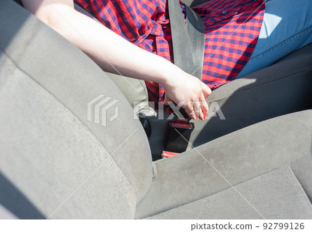 Woman's hand fastens the seat belt of the car for safety before driving on the road. Woman's hand fastens the seat belt of the car for safety before driving on the road. 92799126