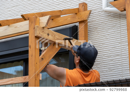 Do-it-yourself man building a wooden pergola 92799988
