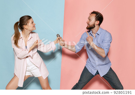 Couple of young funny and happy man and woman having fun isolated over blue and pink background. Human emotions, youth, love and active lifestyle concept 92801191