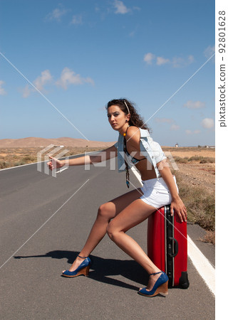 attractive woman hitchhiking on a lonely road 92801628