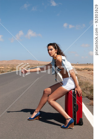 attractive woman hitchhiking on a lonely road 92801629