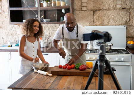 African American father and daughter cooking a dessert together in their home kitchen while recording video for their social media 92801956