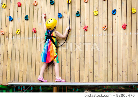 Child in adventure park. Kids climbing rope trail. 92803476