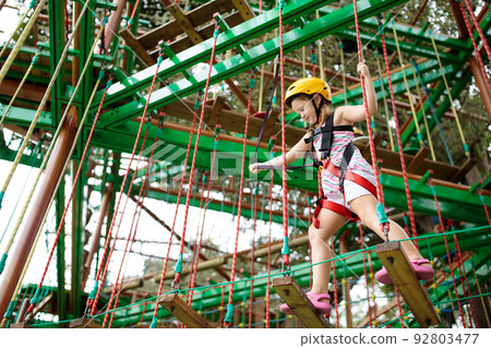 Child in adventure park. Kids climbing rope trail. 92803477