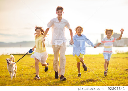 Family with kids running outdoor at sunset. 92803841