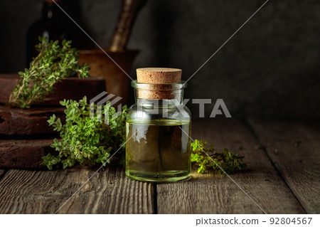 Bottle of thyme essential oil with fresh thyme twigs. 92804567