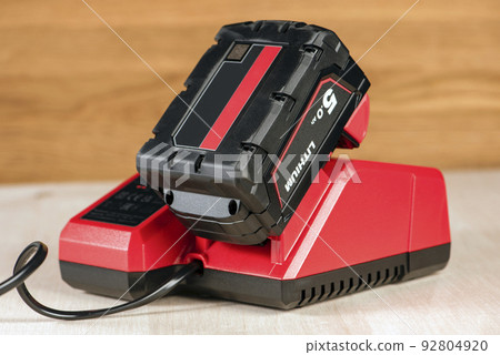 The process of charging a lithium battery from a cordless construction tool. The battery from the screwdriver is charged in the charger 92804920