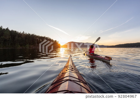 Adventurous Woman on Sea Kayak paddling in the Pacific Ocean. Adventurous Woman on Sea Kayak paddling in the Pacific Ocean. 92804967