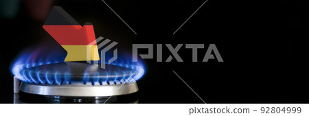 Decreased gas supplies in Germany. A gas stove with a burning flame and an arrow in the colors of the Germany flag pointing down. Concept of crisis in winter and lack of natural gas. Heating season. 92804999