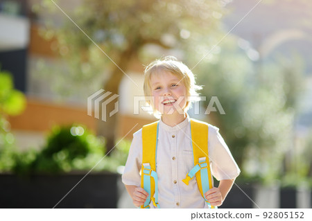 Little schoolboy joyfully goes to school after holiday. Child in a yard of schoolhouse. Education for children. Kids back to school concept. Little schoolboy joyfully goes to school after holiday. Child in a yard of schoolhouse. Education for children. Kids back to school concept. 92805152