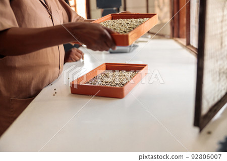 Woman making a selection of coffee beans by fineness using two sieves Woman making a selection of coffee beans by fineness using two sieves 92806007