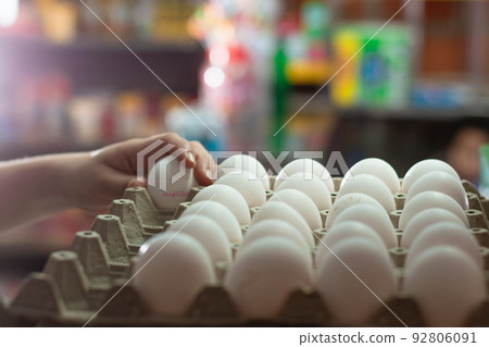 hand of a woman holding white chicken eggs, placed in an egg carton. sale of eggs in a grocery store. eggs rich in protein albumin ready to be sold and consumed in different foods. food concept 92806091