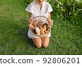 Young woman in white dress sitting on the grass with basket with assorti of brown and white homemade bread. High quality photo 92806201