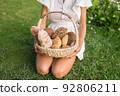 Young woman in white dress sitting on the grass with basket with assorti of brown and white homemade bread. High quality photo 92806211