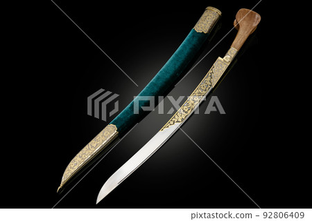 souvenir collectible silver gold dagger cutlass with scabbard, with metal engraving, on black background. Luxury weapons with traditional patterns in medieval vintage style. 92806409