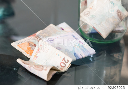 Colombian banknotes on a glass table, in the background a glass jar with money, economy, bankruptcy, personal savings. concept of economy and poverty 92807023
