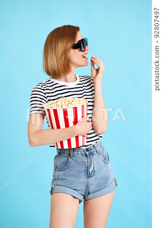 woman watching movie film, holding bucket of popcorn 92807497