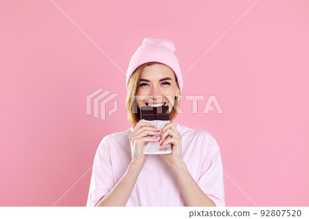 young happy woman in casual t-shirt biting sweet chocolate bar young happy woman in casual t-shirt biting sweet chocolate bar 92807520