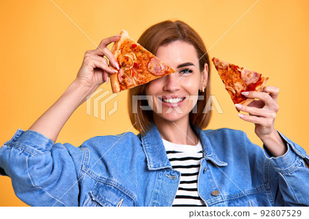woman covering her eyes with a slice of fresh pizza woman covering her eyes with a slice of fresh pizza 92807529