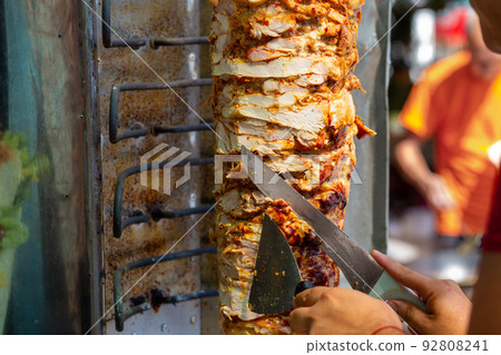 Chef cutting with doner knife Traditional Turkish Doner Kebab meat. Chef cutting with doner knife Traditional Turkish Doner Kebab meat. 92808241
