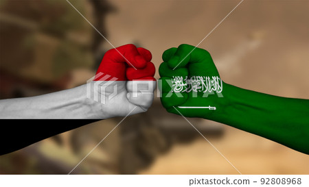 Saudi Arabia vs Yemen. Two fists with national flags for military conflict. On background photo of war out of focus Saudi Arabia vs Yemen. Two fists with national flags for military conflict. On background photo of war out of focus 92808968