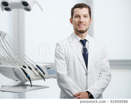 Closeup portrait of smiling male dentist in white lab coat looking at camera 92808996