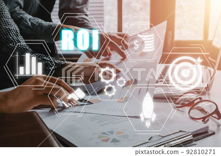 ROI, Return on investment business and technology concept, Business team analyzing income charts and graphs with ROI icon on VR screen. 92810271